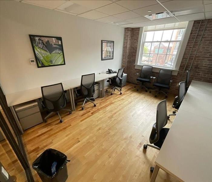 Office area with three desks near wet wall and wood floorboards
