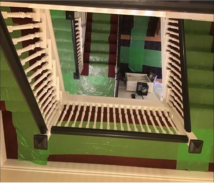 carpeted stairwell covered with green SERVPRO floor protection