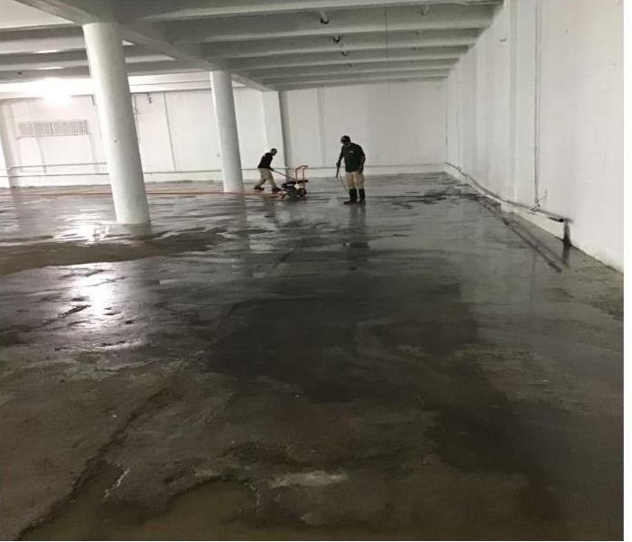 two technicians in garage with water puddles throughout floors